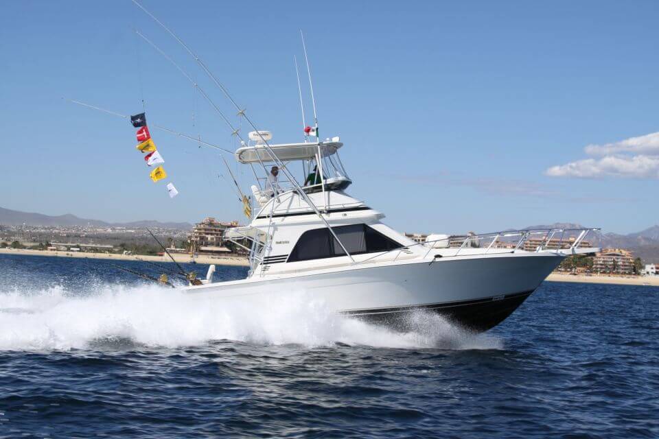 Side of our Cabo fishing charter yacht cruising on ocean with Cabo San Lucas hotels in the background
